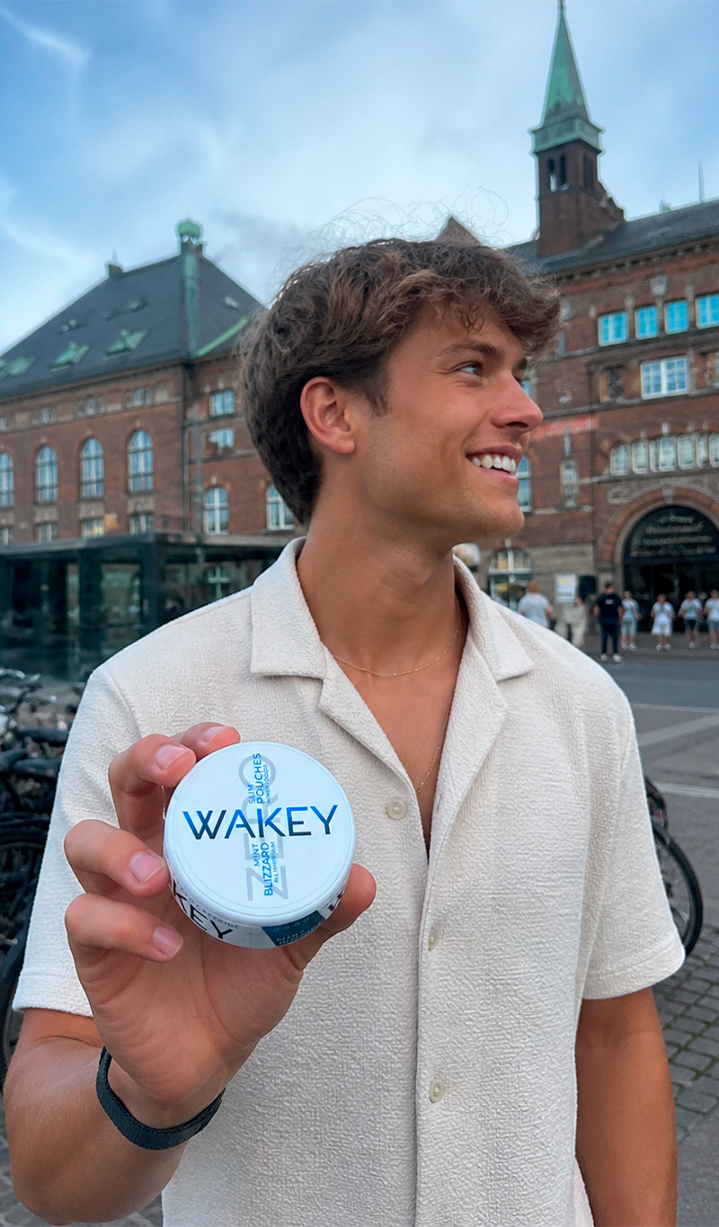 Frau im Café hält eine Dose Wakey Cool Spearmint in die Kamera